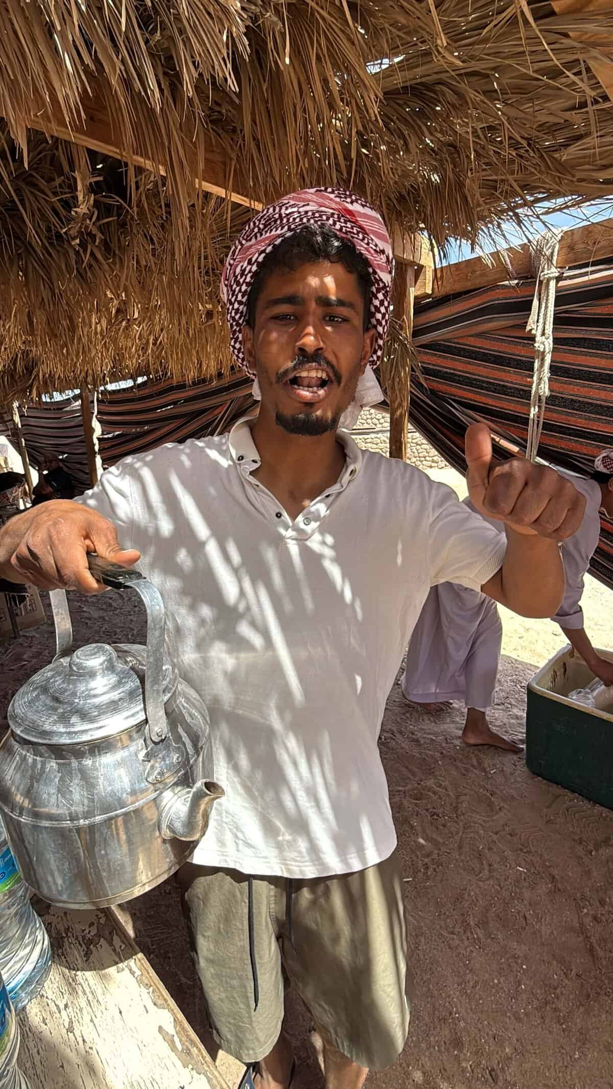 beduino sorride e tiene in mano teiera in una tenda a ras mohammed