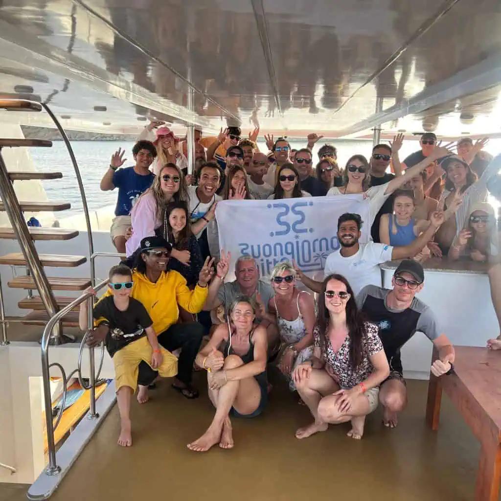 gruppo di persone sorridenti in barca con guida e bandiera di buongiorno egitto