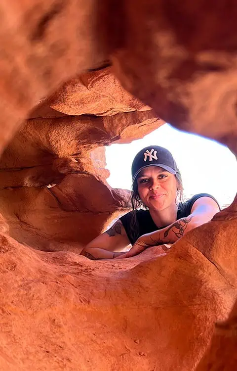 giovane donna sorride attraverso il buco di una delle formazioni rocciose nel canyon rosso vicino nuweiba