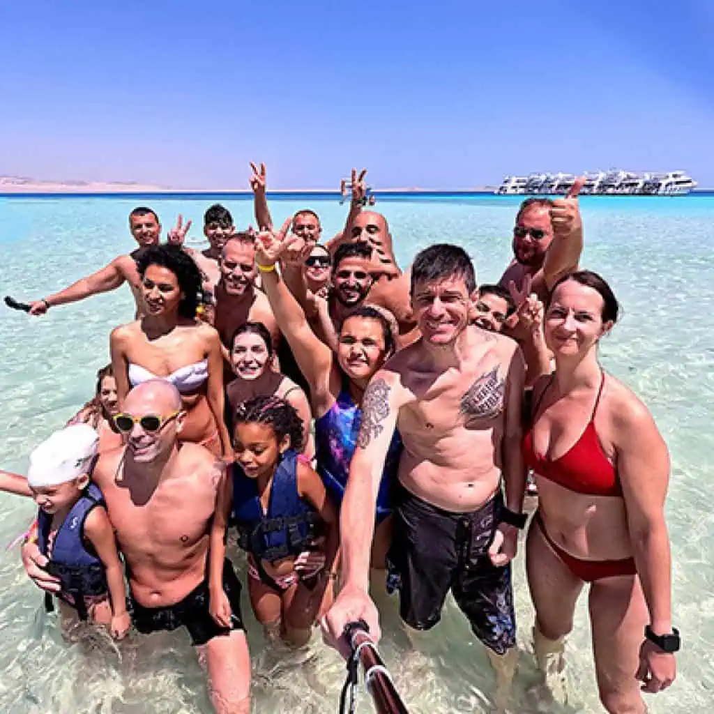 gruppo di clienti si fa un selfie all' isola che non c' e' all orizzonte barche attraccate e le montagne di ras mohammed