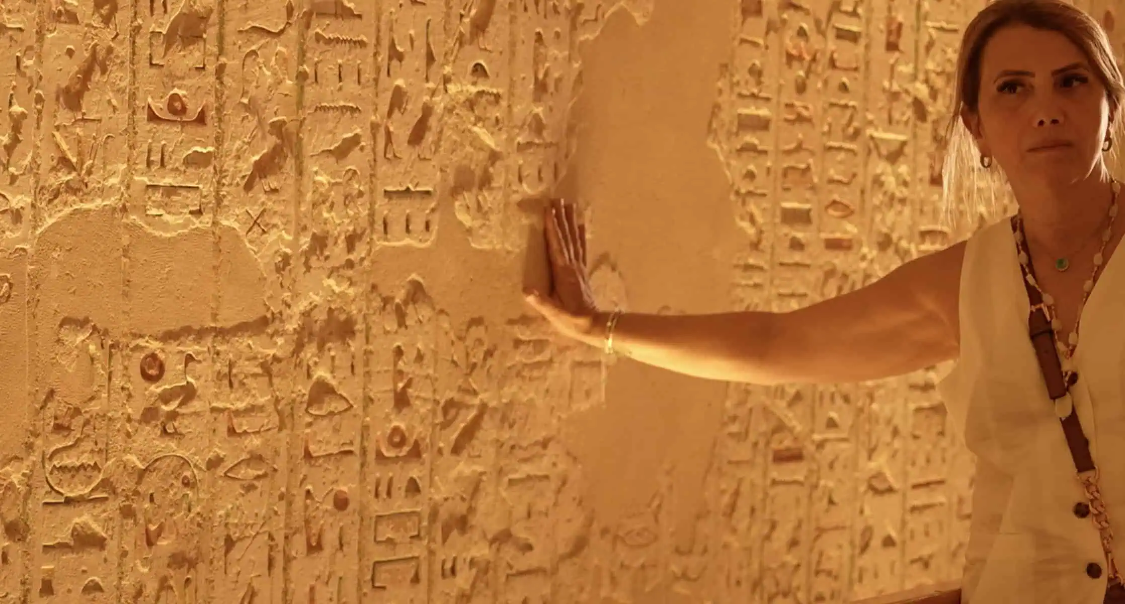 donna bionda tocca i geroglifici all' interno delle tombe alla valle dei re a Luxor